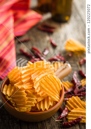 Crispy potato chips in bowl on wooden table. 120225072