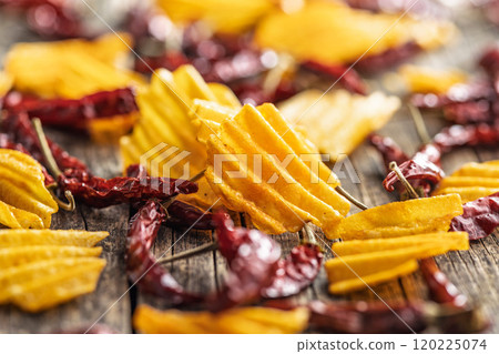 Crispy potato chips and chili peppers on wooden table. Crispy potato chips and chili peppers on wooden table. 120225074