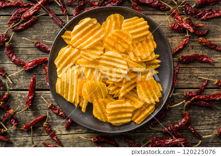 Crispy potato chips on plate on wooden table. Top view. 120225076