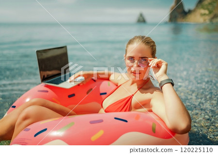 Woman laptop sea. Freelancer woman in sunglases floating on an inflatable big pink donut with a laptop in the sea. People summer vacation rest lifestyle concept 120225110