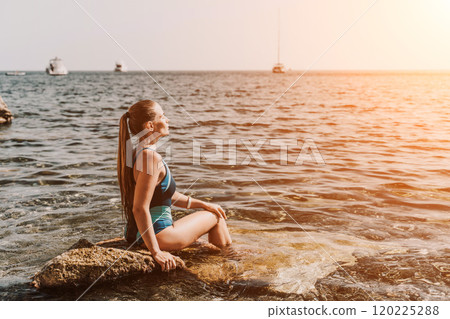 Woman travel summer sea. A happy tourist in a blue bikini enjoying the scenic view of the sea and volcanic mountains while taking pictures to capture the memories of her travel adventure. Woman travel summer sea. A happy tourist in a blue bikini enjoying the scenic view of the sea and volcanic mountains while taking pictures to capture the memories of her travel adventure. 120225288