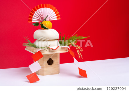 A photo of "Kagami-mochi" (real rice cake) placed on the left, with a red and white background and a sanpo (pedestal) A photo of "Kagami-mochi" (real rice cake) placed on the left, with a red and white background and a sanpo (pedestal) 120227004