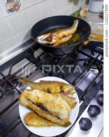 fried fish lies on a plate and in a frying pan fried fish lies on a plate and in a frying pan 120227800