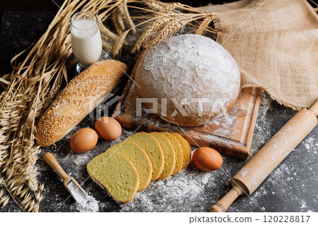 Freshly baked bread with eggs, milk, and wheat on table, showcasing natural baking ingredients Freshly baked bread with eggs, milk, and wheat on table, showcasing natural baking ingredients 120228817