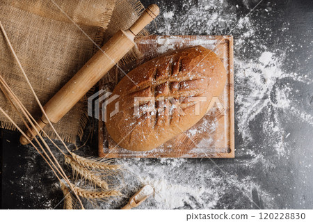 Freshly baked artisan bread with wheat spikes and flour on rustic background 120228830