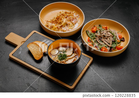 A flavorful trio of pasta, salad, and soup with bread, perfect for a balanced and satisfying meal 120228835