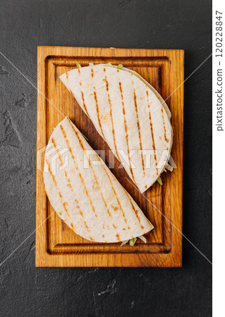 Grilled tortilla wraps with fresh veggies on a wooden board for a quick and tasty meal Grilled tortilla wraps with fresh veggies on a wooden board for a quick and tasty meal 120228847
