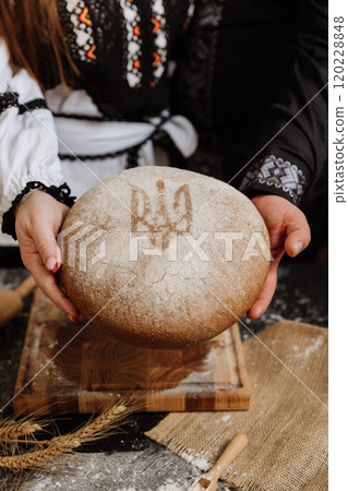 Traditional Ukrainian bread with national emblem held in hands, symbolizing heritage and unity Traditional Ukrainian bread with national emblem held in hands, symbolizing heritage and unity 120228848
