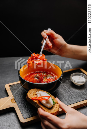 Close-up of authentic Ukrainian borscht with rye bread, sour cream, and chili pepper garnish 120228856