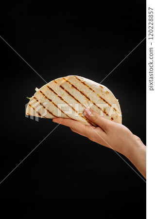 Grilled tortilla wrap with fresh filling held in hand, a perfect grab-and-go snack or lunch option Grilled tortilla wrap with fresh filling held in hand, a perfect grab-and-go snack or lunch option 120228857