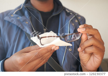 cleaning eyeglass with tissue close up  120230377
