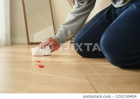 A person is diligently cleaning red stains that have appeared on their wooden floor surface A person is diligently cleaning red stains that have appeared on their wooden floor surface 120230404