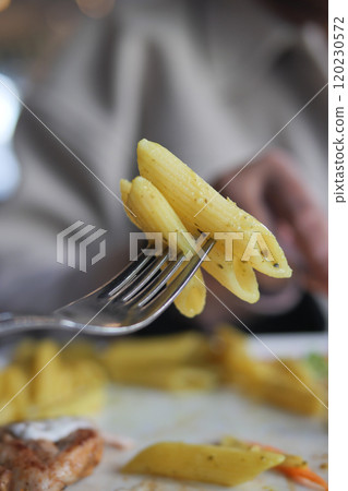 A delicious plate of Penne Pasta balanced on a fork, ready to be enjoyed and savored 120230572