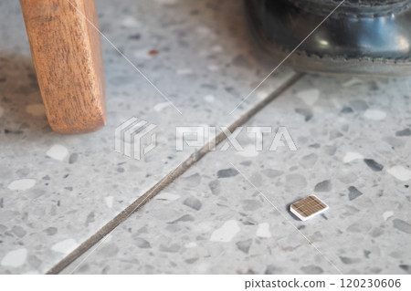 a phone sim card dropped on a tiles floor. lost sim card concept  120230606