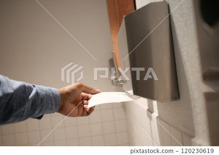 Hand Using Paper Towel Dispenser in a Hygienic Public Restroom with Clean White Tiles Hand Using Paper Towel Dispenser in a Hygienic Public Restroom with Clean White Tiles 120230619