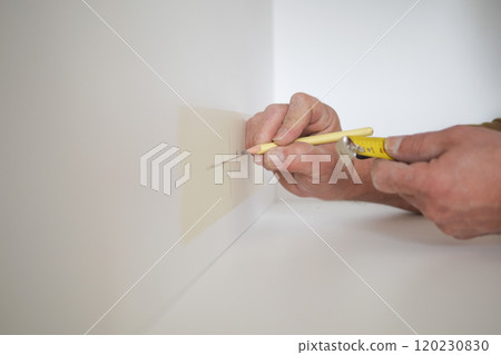 Man measuring wall with a tape measure  120230830