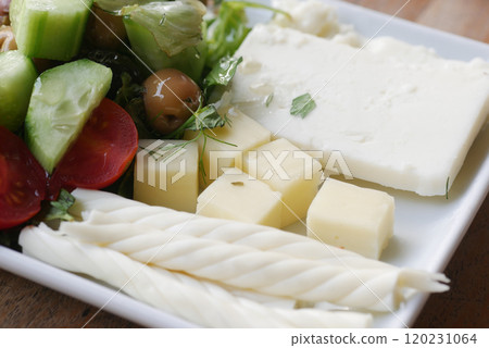Enjoy a delicious cheese platter with fresh vegetables and greens for a delightful meal 120231064