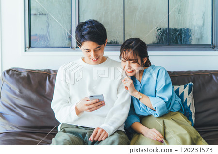 A young couple looking at a smartphone together 120231573
