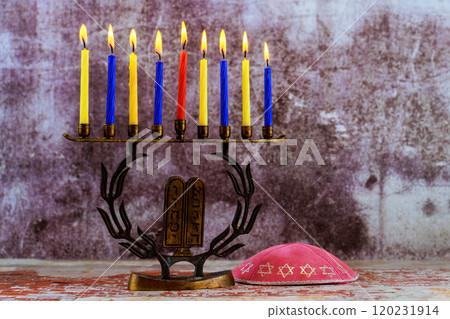 Menorah with nine lit candles, kippah resting on a wooden table of Jewish tradition holiday Hanukkah is symbolizing light 120231914