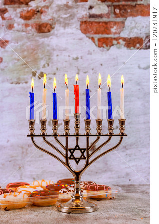 Hanukkah menorah with nine lit candles kippah resting on wooden table symbolizes light of Jewish holiday 120231917