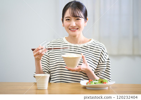 Young woman eating rice Young woman eating rice 120232404