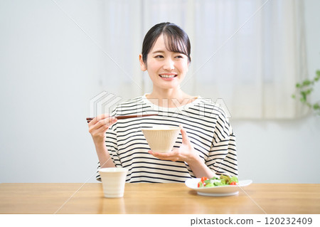 Young woman eating rice 120232409