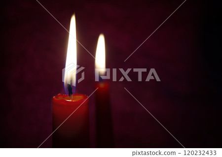 Red candles with a bright flame, set against a textured dark background. The flame flickers gently, casting a warm glow and creating a serene atmosphere. 120232433