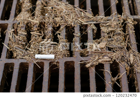廢棄香菸被沖到池塘柵欄上並留在那裡的場景。 120232470