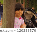 Hide and seek: A girl peeking out from behind a tree 120233570