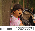 Hide and seek: A girl peeking out from behind a tree 120233571