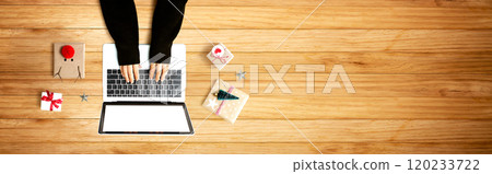 Person using a laptop computer with Christmas gift boxes 120233722
