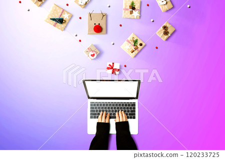 Person using a laptop computer with Christmas gift boxes 120233725