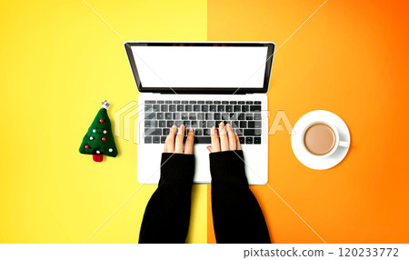 Person using a laptop computer with a Christmas tree cushion and a cup of coffee Person using a laptop computer with a Christmas tree cushion and a cup of coffee 120233772