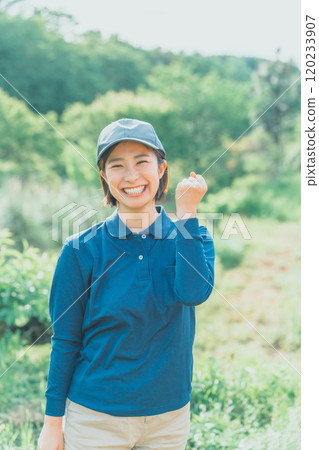 A young woman in a blue polo shirt is doing a fist pump in the middle of lush nature A young woman in a blue polo shirt is doing a fist pump in the middle of lush nature 120233907