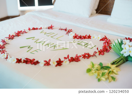 message WILL YOU MARRY ME made of flower petals with bouquet and Heart shape on bed. Idea for marriage proposal, romantic surprise, wedding and engagement concept 120234050