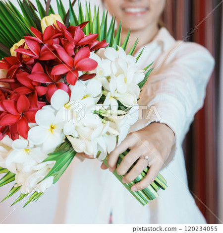 Woman hand wearing a diamond ring and holding flower bouquet. Idea for marriage proposal, romantic surprise, wedding, engagement and valentines day concept 120234055