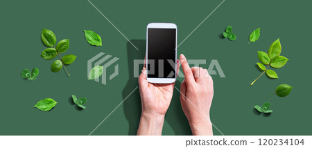 Person using a smartphone with green leaves 120234104