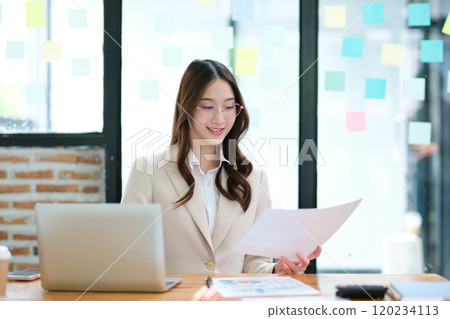 Businesswoman analyzing financial data and managing online investments 120234113