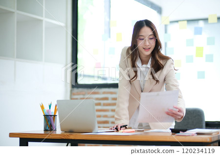 Businesswoman analyzing financial data and managing online investments 120234119