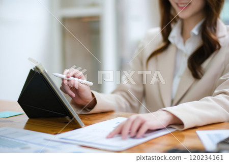 Businesswoman analyzing charts and using a tablet for data review Businesswoman analyzing charts and using a tablet for data review 120234161