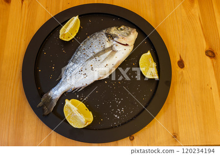 Raw fresh fish dorado with lemon and spices on wooden table. Top view 120234194