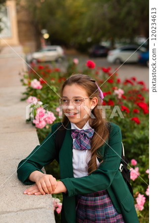 Girl in school uniform surrounded by blooming flowers. 120234613