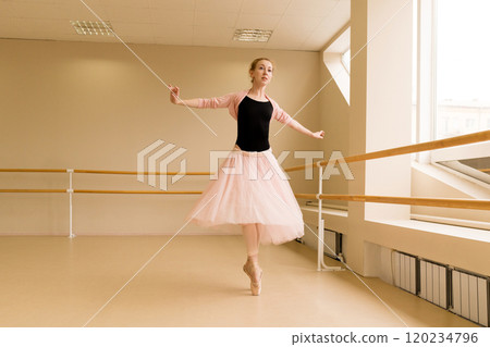 Ballet dancer spinning en pointe in well-lit dance studio 120234796