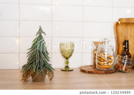 Christmas tree on a table next to a wine glass and a jar of dried fruit Christmas tree on a table next to a wine glass and a jar of dried fruit 120234995