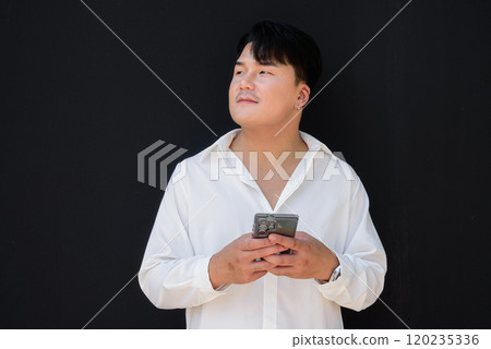Portrait of Handsome Young Asian Man Against Black Background 120235336