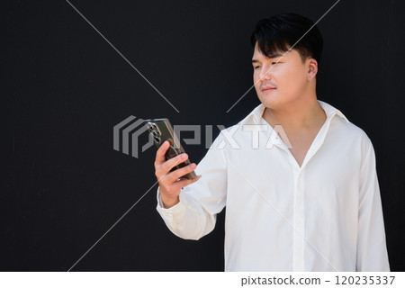 Portrait of Handsome Young Asian Man Against Black Background 120235337