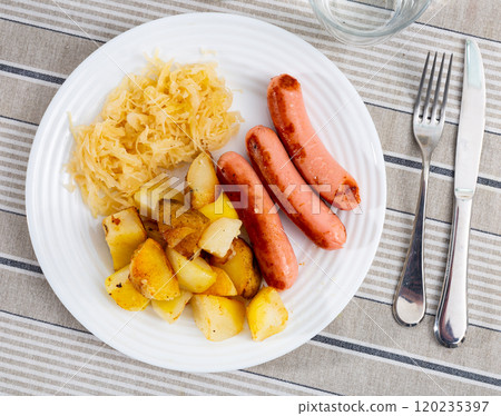 Fried sausages with roasted potato slices and stewed cabbage 120235397