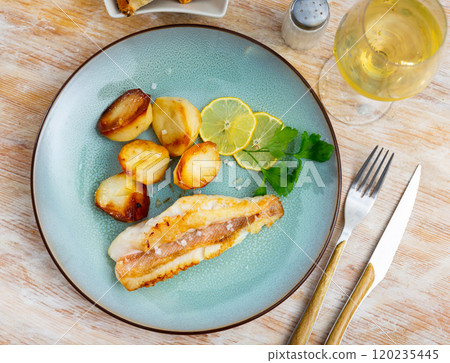 Fried Gallineta fish fillet with potatoes and parsley closeup 120235445