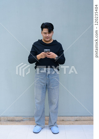 Full Length Portrait of Handsome Young Asian Man Against Plain Background Outdoors 120235484