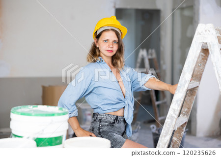 Sexy woman in denim shirt and shorts next to a stepladder in room being renovated Sexy woman in denim shirt and shorts next to a stepladder in room being renovated 120235626